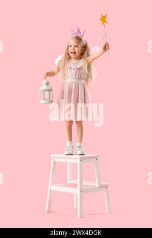 Graziosa piccola fata con lanterna sullo sgabello su sfondo rosa Foto Stock