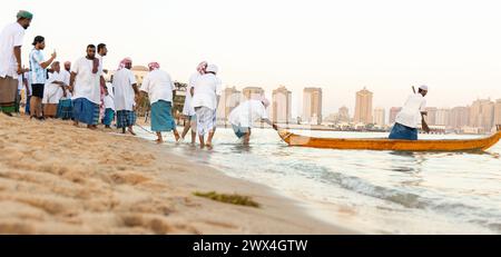 I pescatori arabi su un'antica barca di legno vanno a pescare al tramonto. Conservazione delle tradizioni nazionali, dell'artigianato antico, dello stile di vita storico Foto Stock