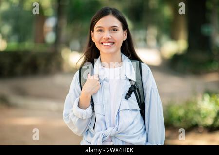 Giovane donna sorridente con lunghi capelli scuri che indossa una camicia bianca Foto Stock
