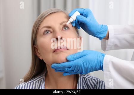 Gocce mediche. Medico che gocciola il farmaco nell'occhio della donna in ambienti chiusi Foto Stock