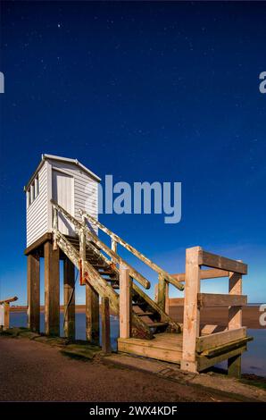 Una vista notturna al chiaro di luna con un cielo limpido e l'aurora boreale del rifugio sulla strada rialzata di Lindisfarne nel Northumberland Foto Stock