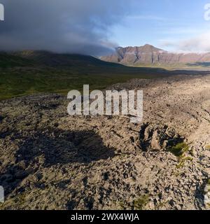 Una veduta della strada sterrata che si estende all'orizzonte tra i campi di lava. Vista dall'alto, foto scattata dal drone. Helgafellssveit, Islanda. Foto Stock