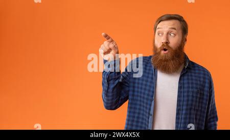 Amazed Redhaired Man che punta le dita a parte a Empty Space, Studio Foto Stock
