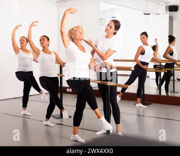 Varie donne anziane che esercitano il balletto si muove con il formatore Foto Stock