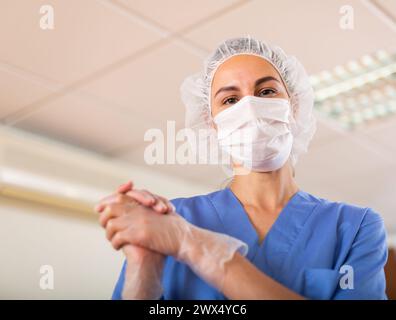 L'infermiera femminile in maschera indossa guanti monouso Foto Stock