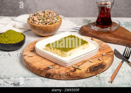 Dessert Kadayif con pistacchio e latte. Kadayif freddo con cioccolato su un tavolo da servizio in legno. Famosi piatti della cucina turca Foto Stock