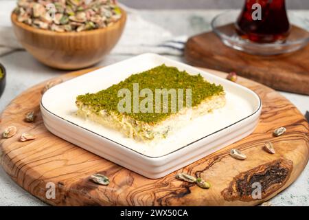 Dessert Kadayif con pistacchio e latte. Kadayif freddo con cioccolato su un tavolo da servizio in legno. Famosi piatti della cucina turca Foto Stock