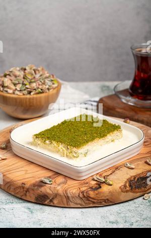 Dessert Kadayif con pistacchio e latte. Kadayif freddo con cioccolato su un tavolo da servizio in legno. Famosi piatti della cucina turca Foto Stock