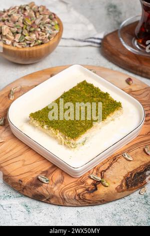 Dessert Kadayif con pistacchio e latte. Kadayif freddo con cioccolato su un tavolo da servizio in legno. Famosi piatti della cucina turca Foto Stock