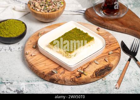 Dessert Kadayif con pistacchio e latte. Kadayif freddo con cioccolato su un tavolo da servizio in legno. Famosi piatti della cucina turca Foto Stock