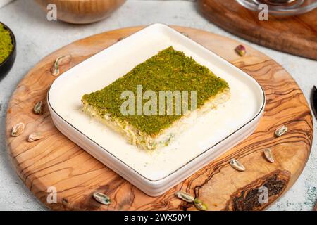 Dessert Kadayif con pistacchio e latte. Kadayif freddo con cioccolato su un tavolo da servizio in legno. Famosi piatti della cucina turca Foto Stock