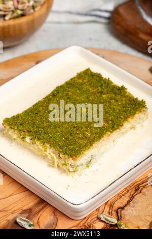 Dessert Kadayif con pistacchio e latte. Kadayif freddo con cioccolato su un tavolo da servizio in legno. Famosi piatti della cucina turca Foto Stock