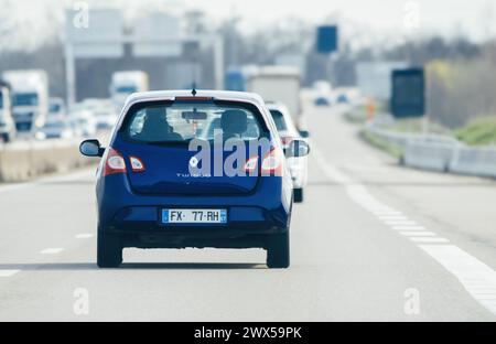 Strasburgo, Francia - 20 marzo 2024: Una Renault Twingo che guida su un'autostrada francese con traffico sullo sfondo, catturando il flusso dei trasporti giornalieri nella regione Foto Stock