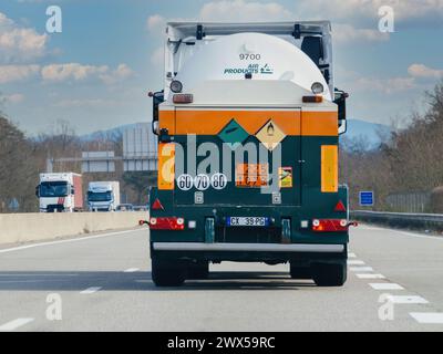 Strasburgo, Francia - 20 marzo 2024: Un grande camion dipinto di verde e arancione percorre una strada, circondato dal traffico e dai dintorni urbani. Foto Stock