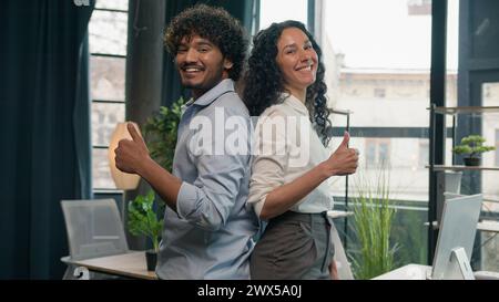 Entusiasti colleghi multirazziali partner commerciali uomo d'affari indiano arabo e donna ispanica colleghi d'affari che guardano alla telecamera felice Foto Stock