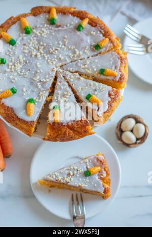 Torta di carote cosparsa di noci decorata con carote color crema Foto Stock