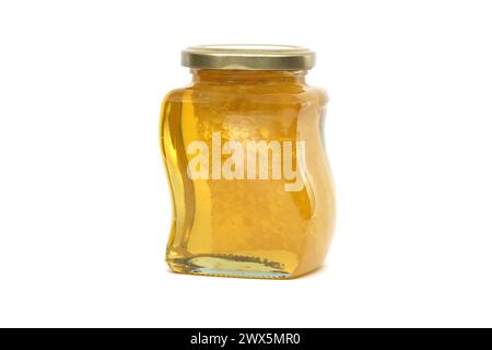 Un vaso di vetro con coperchio dorato contiene miele con favo riempito quasi fino in cima, su sfondo bianco Foto Stock