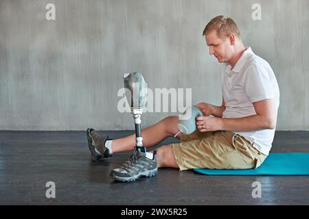 Uomo, amputato e gamba protesica in palestra seduta da attaccare, arto residuo da assemblare. Palestra, fisioterapia e fitness per il benessere maschile Foto Stock