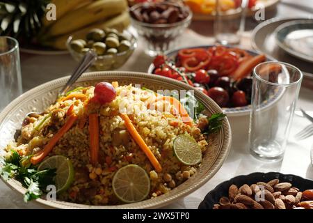 Primo piano selettivo del pilaf decorato con fette di lime, carote e uva sul tavolo festivo preparato per la celebrazione di Eid al-Fitr Foto Stock