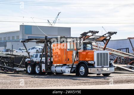 Carro industriale, camion di grandi dimensioni arancione, semirimorchio con semirimorchio idraulico vuoto a due livelli, in piedi nel parcheggio del magazzino wain Foto Stock