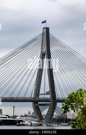 Anzac Bridge attraverso Johnstons Bay, nell'entroterra ovest di Sydney, bandiera australiana che sventola in cima al ponte, Sydney, NSW, Australia Foto Stock