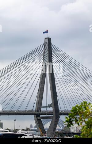 Anzac Bridge attraverso Johnstons Bay, nell'entroterra ovest di Sydney, bandiera australiana che sventola in cima al ponte, Sydney, NSW, Australia Foto Stock