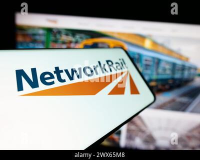 Smartphone con logo della società di infrastrutture ferroviarie Network Rail Limited di fronte al sito Web aziendale. Mettere a fuoco la parte sinistra del display del telefono. Foto Stock