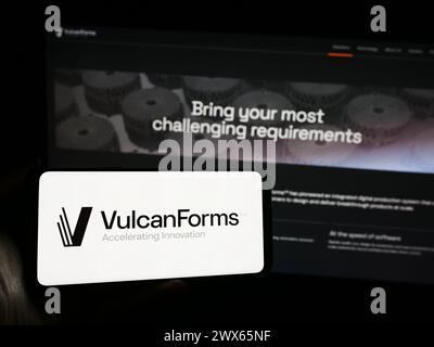 Persona che possiede uno smartphone con il logo della società di produzione digitale americana VulcanForms Inc. Davanti al sito Web. Mettere a fuoco il display del telefono. Foto Stock