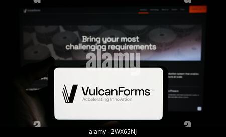 Persona che detiene un cellulare con il logo della società di produzione digitale americana VulcanForms Inc. Di fronte alla pagina Web aziendale. Mettere a fuoco il display del telefono. Foto Stock