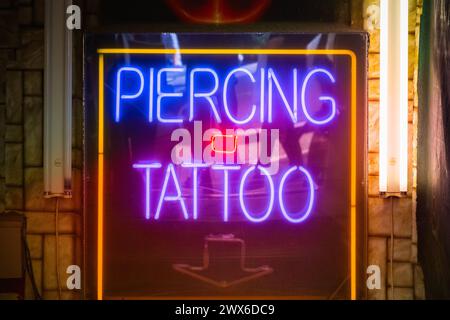 Piercing e tatuaggio all'insegna del neon in mostra al mercato di Camden a Londra, Regno Unito Foto Stock