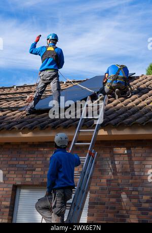 Tre operai che installano pannelli solari. Energia solare Foto Stock