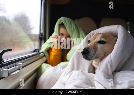 Ragazzo con il suo cane nel letto di un camper coperto di piumini Foto Stock