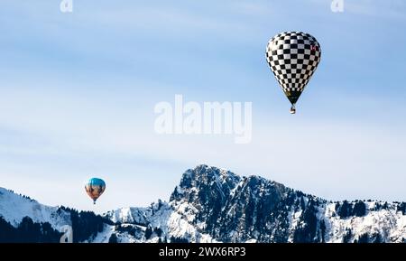 In questa accattivante immagine, due mongolfiere attraversano il cielo con grazia sullo sfondo di maestose montagne innevate. Uno dei palloncini Foto Stock