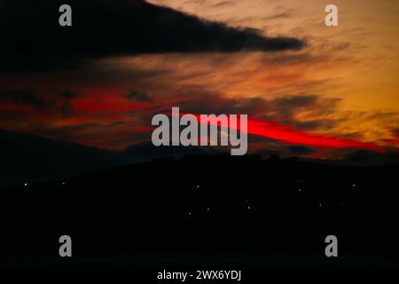 Nel tranquillo crepuscolo, un tramonto rosso inonda il cielo di sfumature ardenti, creando uno spettacolo suggestivo e celeste all'orizzonte. Foto Stock