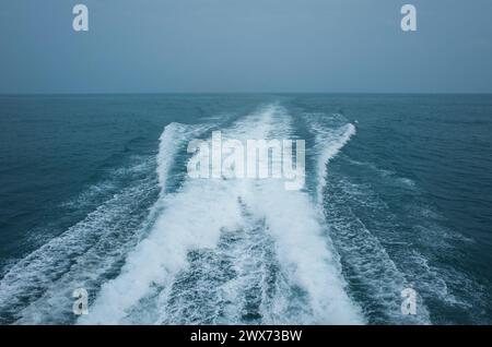 Percorso sulla superficie dell'acqua dietro un catamarano ad alta velocità nel Golfo della Thailandia in condizioni di clima grigio Foto Stock