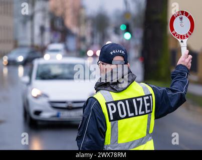 Trebbin, Germania. 22 marzo 2024. Durante una fermata del traffico a Berliner Straße, un agente di polizia fa uscire un veicolo dalla strada con una cazzuola con le parole "Halt Polizei" ("Stop Police"). Credito: Soeren Stache/dpa/Alamy Live News Foto Stock