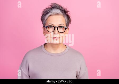 Foto ritratto di una donna d'affari sicura di sé in età matura con felpa viola occhiali da vista costosi isolati su sfondo di colore rosa Foto Stock