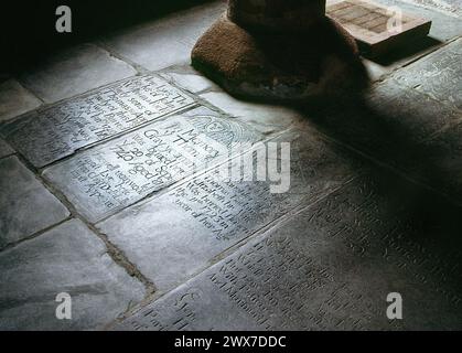 Chiesa di Sant'Endelienta, Sant'Endellione, Wadebridge, Cornovaglia, lapidi sepolcrali del 18° secolo collocate sul pavimento attorno alla base del font. Foto Stock