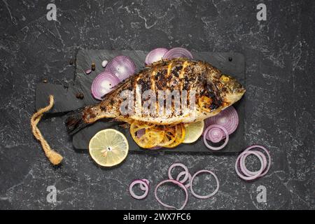 Pesce al forno dorado. Orata o pesce dorada grigliato su sfondo scuro. vista dall'alto. Foto Stock