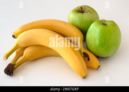 Tagliare le mele verdi e un mucchio di banane su sfondo bianco Foto Stock