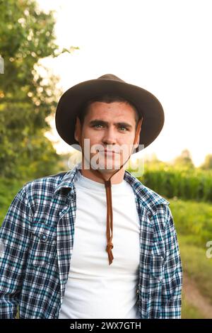 Un giovane agricoltore in piedi con orgoglio in un lussureggiante campo di soia verde, che rappresenta la dedizione e il duro lavoro dei professionisti agricoli nella coltivazione Foto Stock