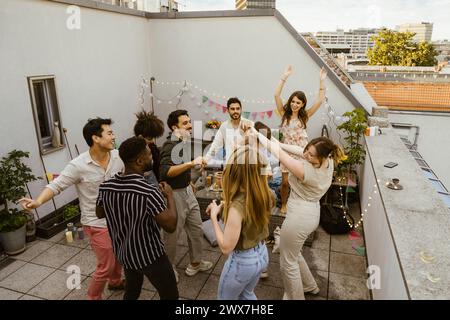 Vista dall'alto di amici multirazziali e uomini che ballano in balcone durante la festa Foto Stock