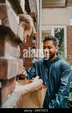 Persona sorridente che consegna il pacco all'uomo a due passi Foto Stock