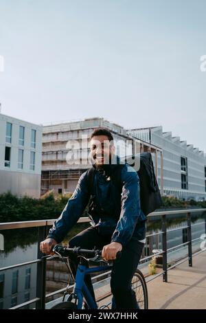 Ritratto di un giovane uomo sorridente che fa la consegna in bicicletta sul sentiero della città Foto Stock