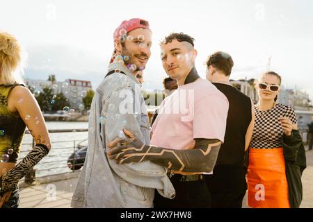 Vista laterale ritratto di un uomo gay in piedi con una persona non binaria sul lungomare della città Foto Stock