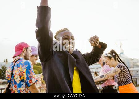 Allegra persona non binaria che balla con gli amici in sottofondo Foto Stock