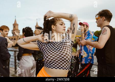 Giovane e spensierato non binario che balla con gli amici in sottofondo Foto Stock