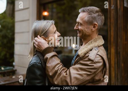 Vista laterale dell'uomo sorridente che accarezza una donna mentre si trova di fronte al ristorante Foto Stock