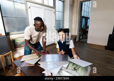 Architetti di sesso maschile e femminile che discutono di un campione di materiale da costruzione in studio Foto Stock