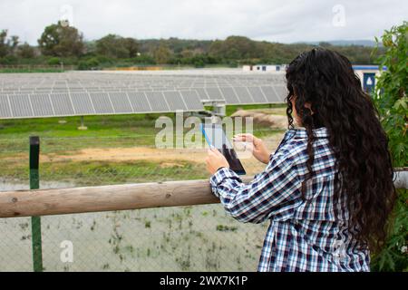 un ingegnere che controlla le prestazioni dei pannelli solari con il suo tablet. Foto Stock